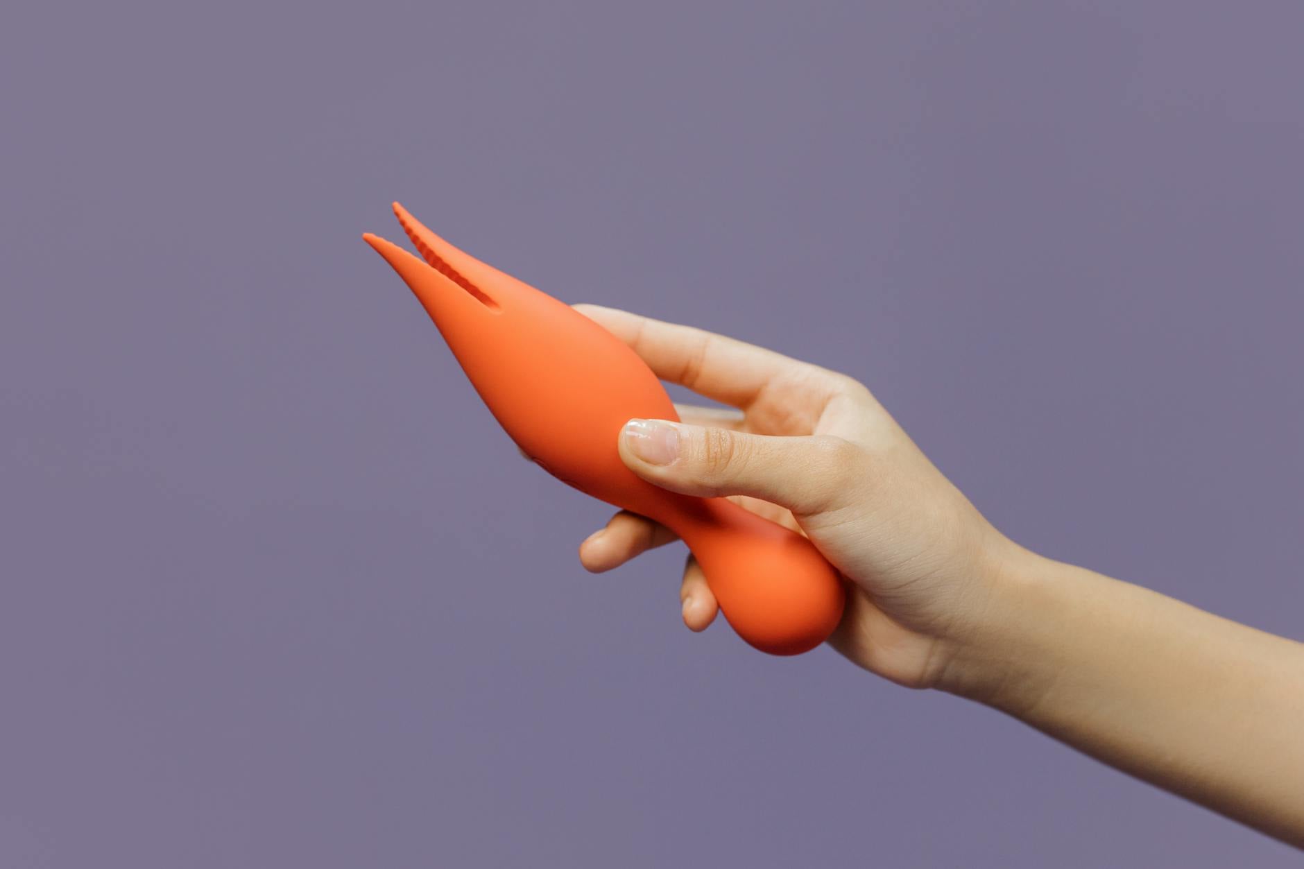 A hand holding a lemon clitoral vibrator against a purple backdrop, symbolizing pleasure and intimate wellness.