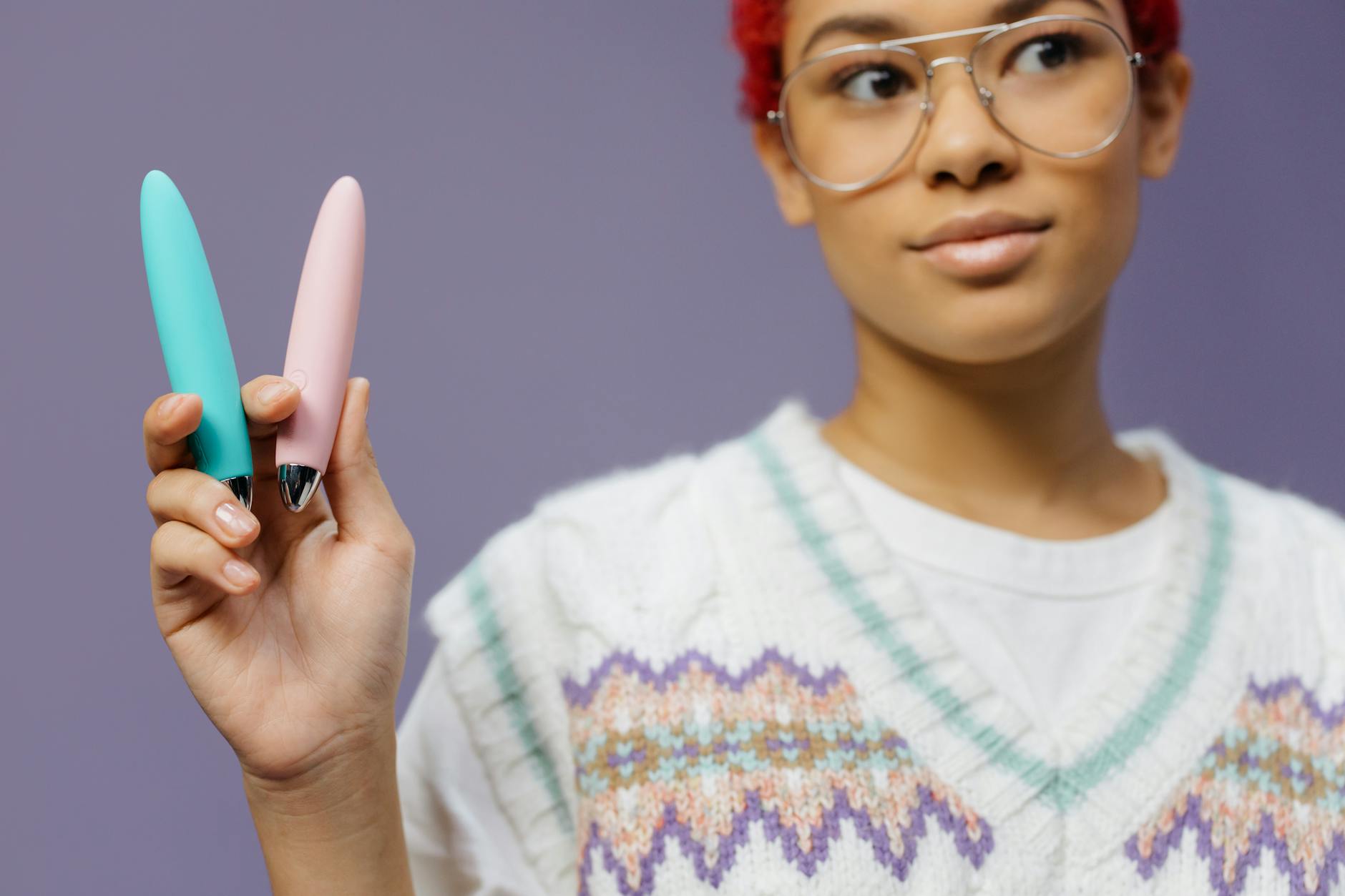 A woman holding two colorful lemon vibrators against a purple background