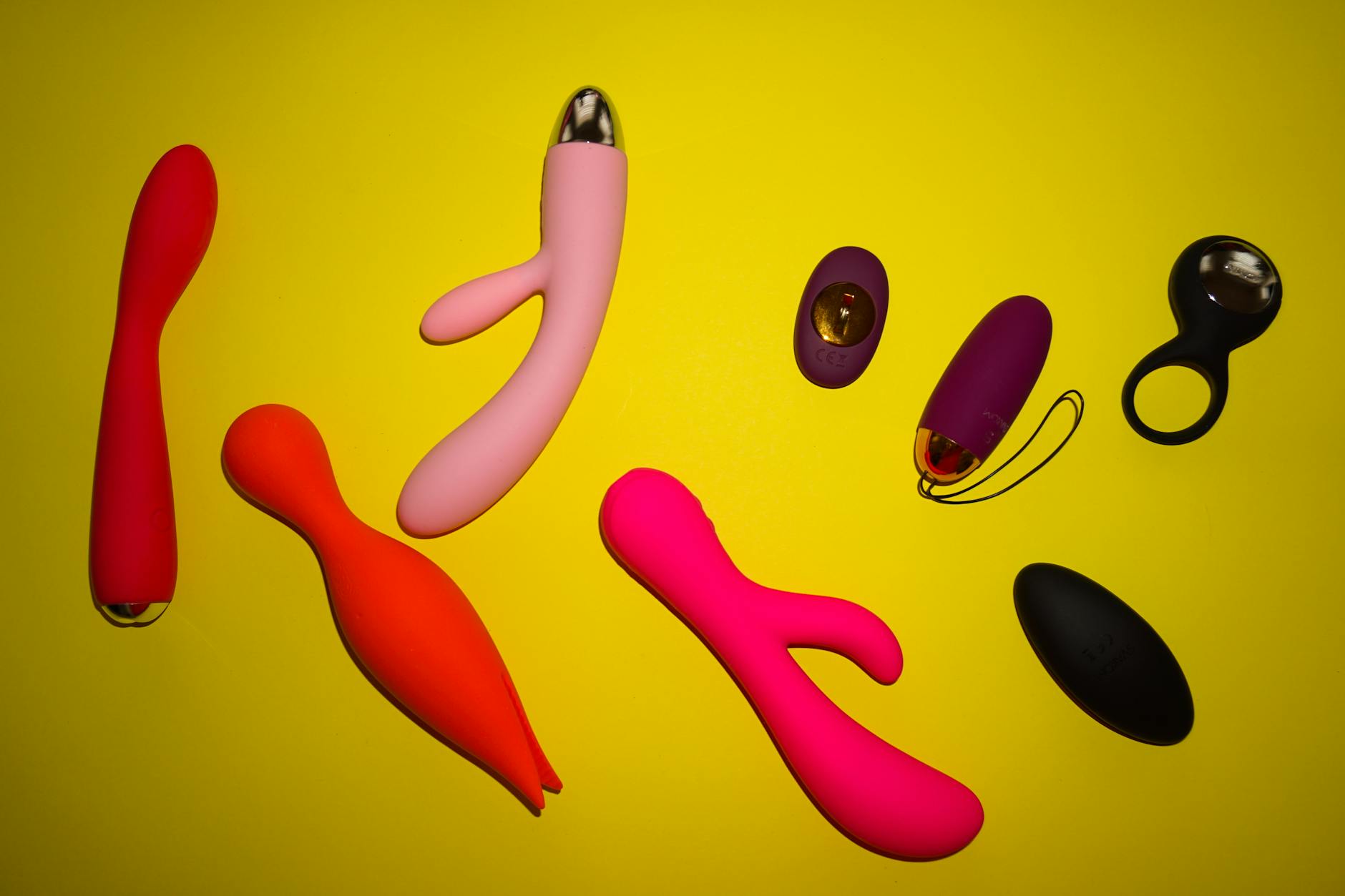 A hand holding an orange vibrator against a purple backdrop, representing gentle sensory control