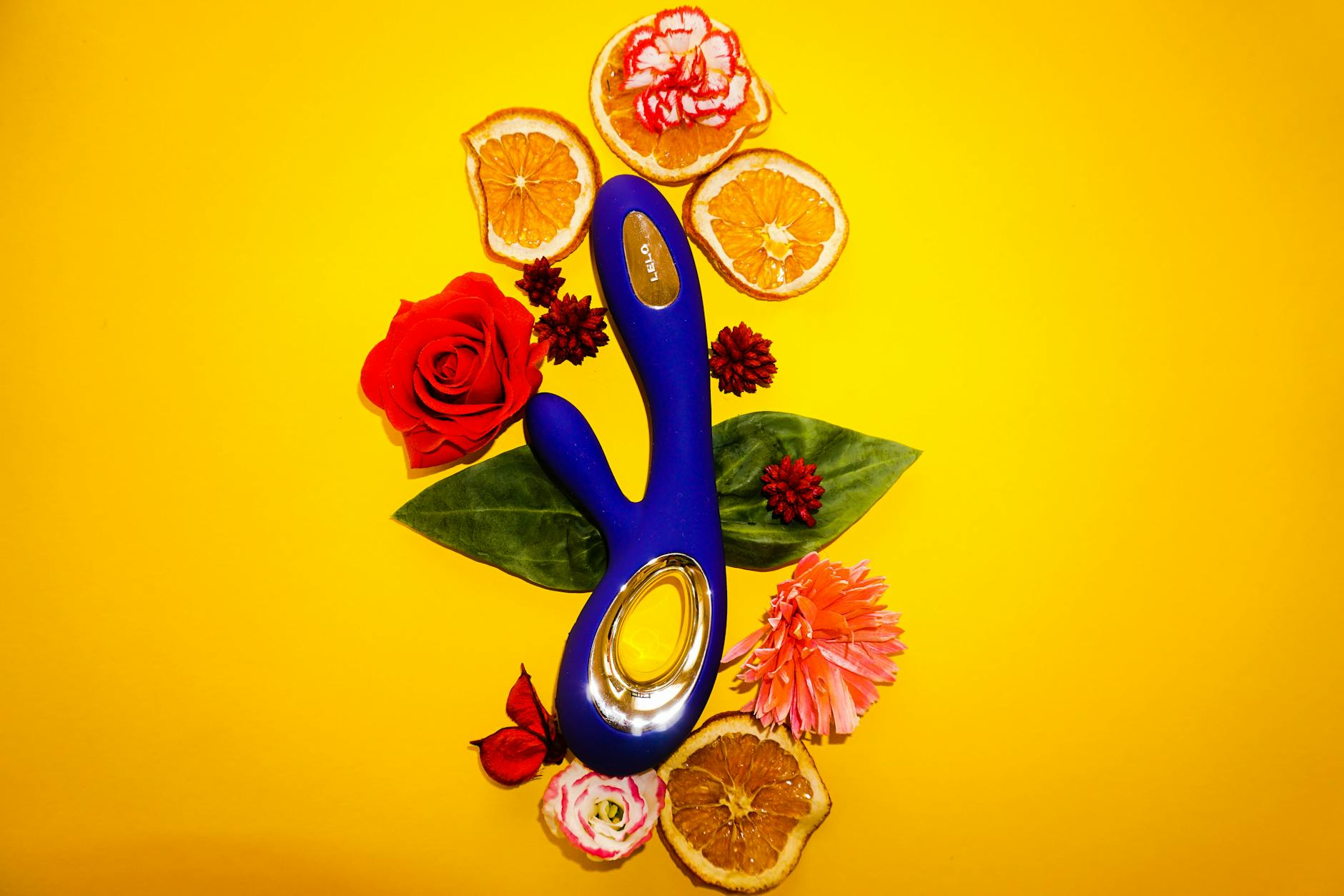 Lemon vibrator surrounded by fresh citrus and flowers on bright yellow background
