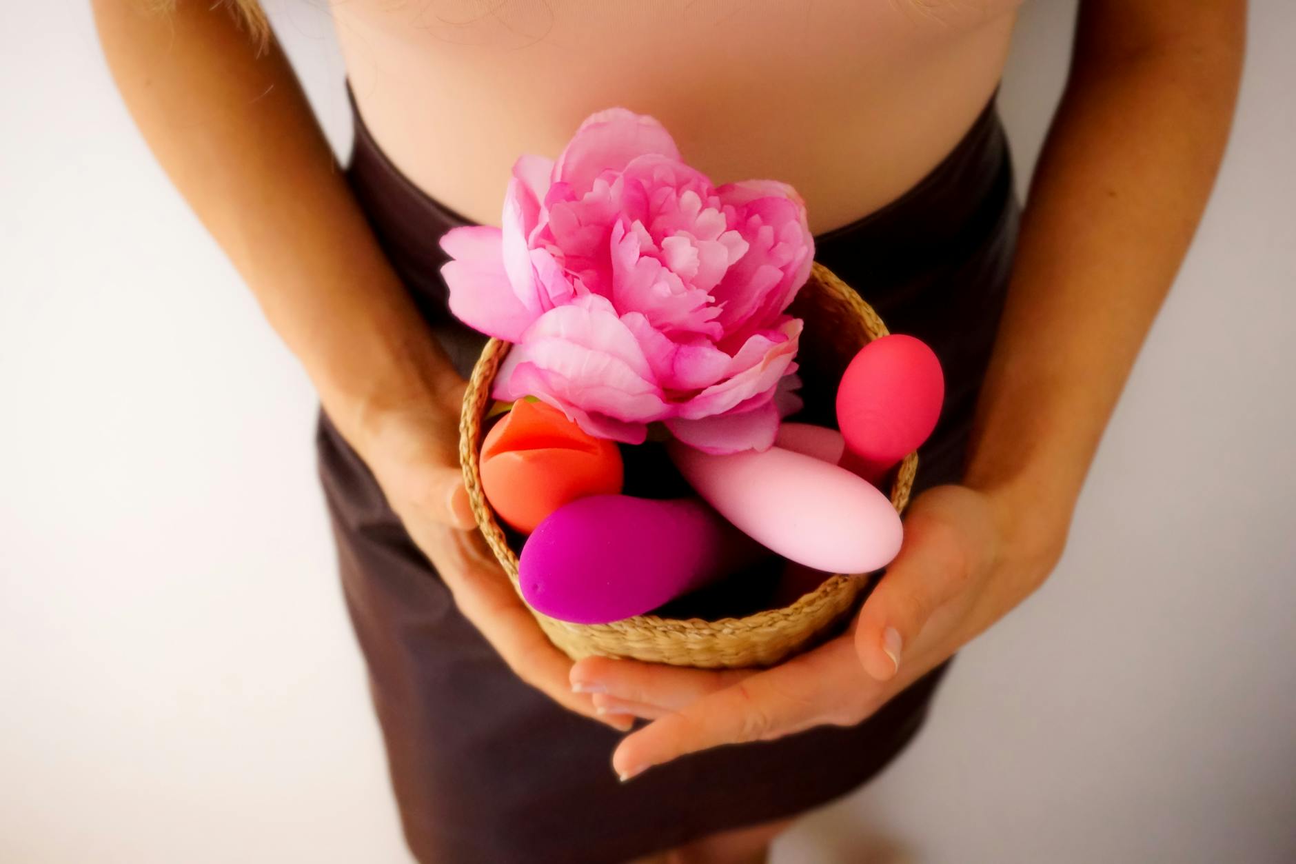 A basket of colorful vibrators and toys with fresh flowers, representing renewed openness to shared pleasure